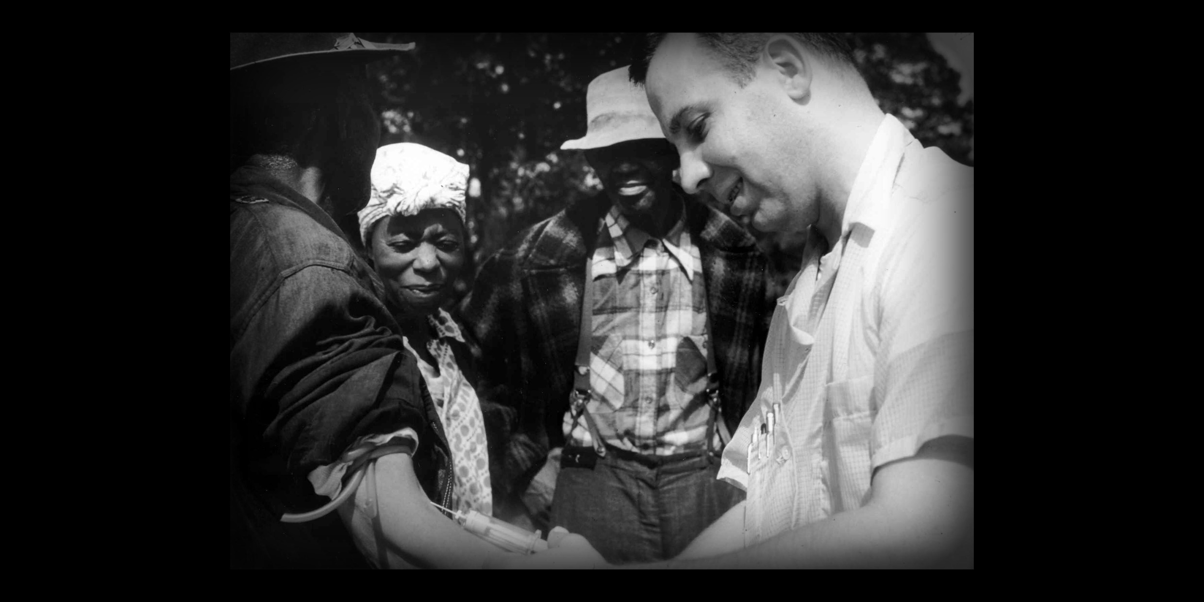 Image of white doctor drawing blood from black patient