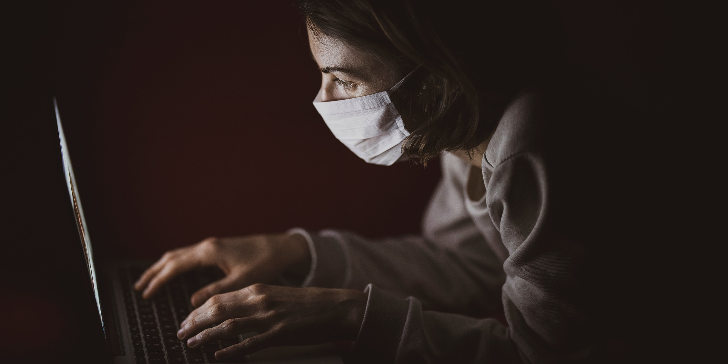 Image of woman wearing mask working at computer