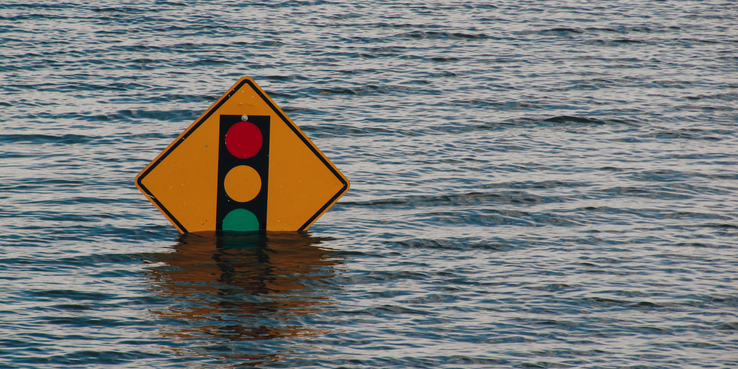 Image of traffic sign partially submerged by floodwater