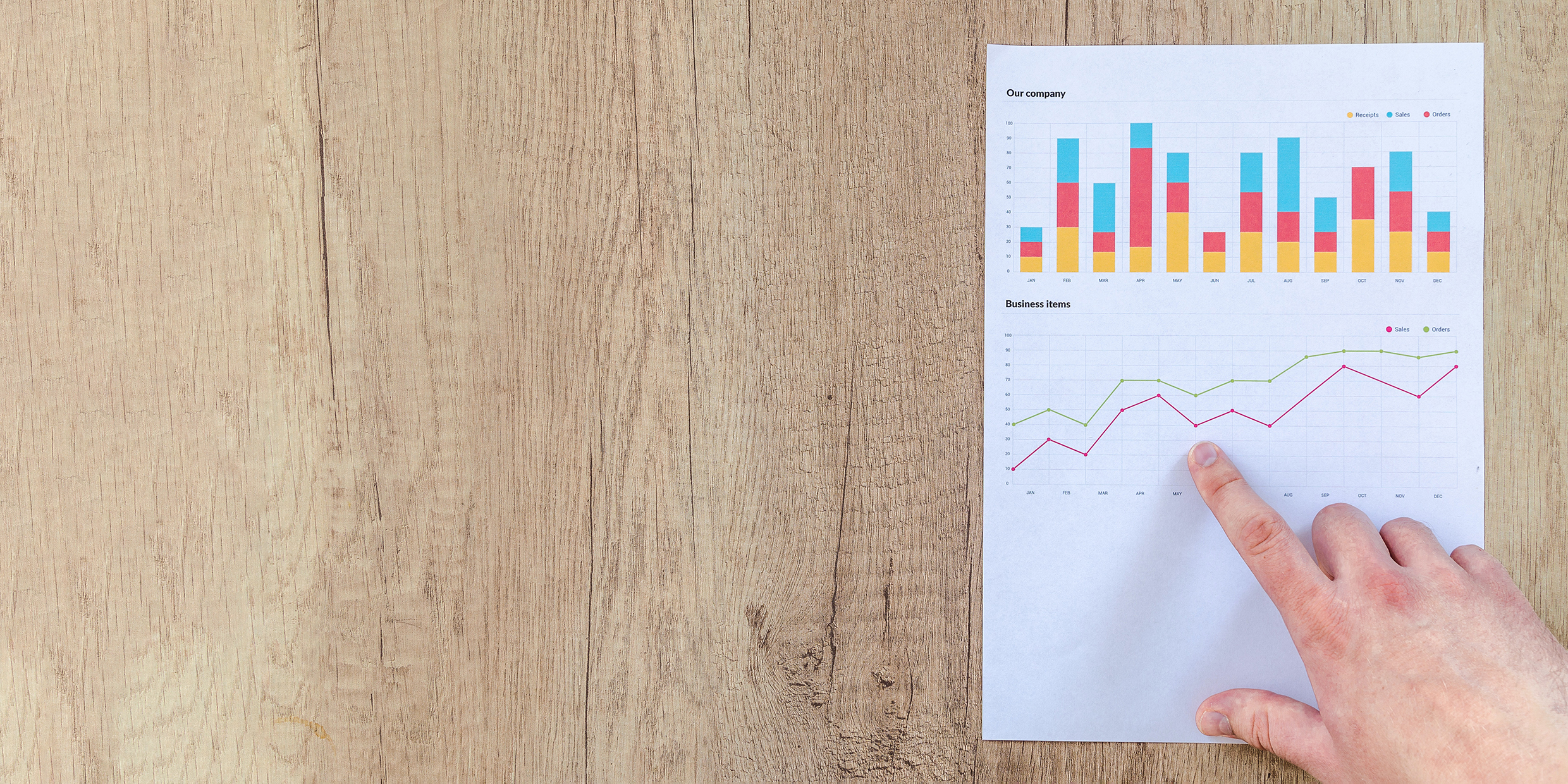 Image of man's hand pointing at charts on paper