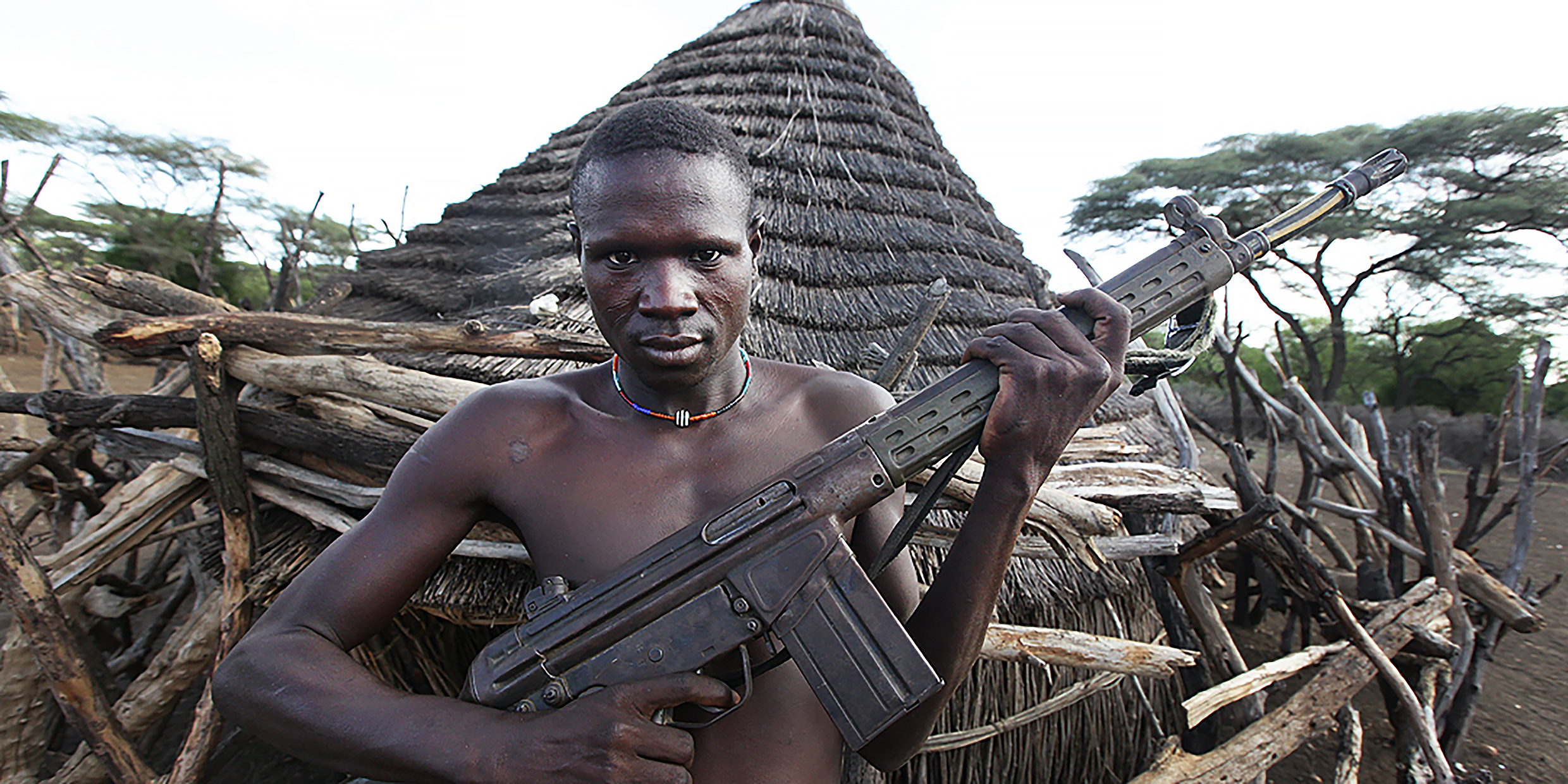 Image of a young Sudanese man posing with an automatic rifle