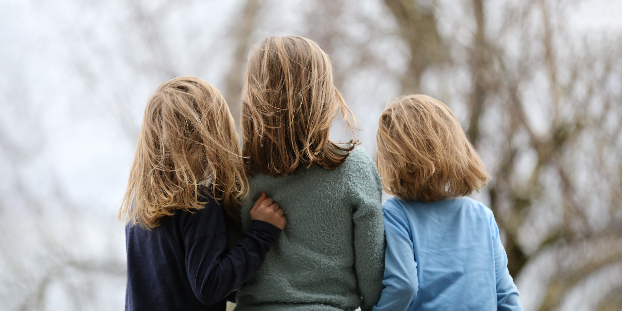 Image of three young siblings viewed from the back