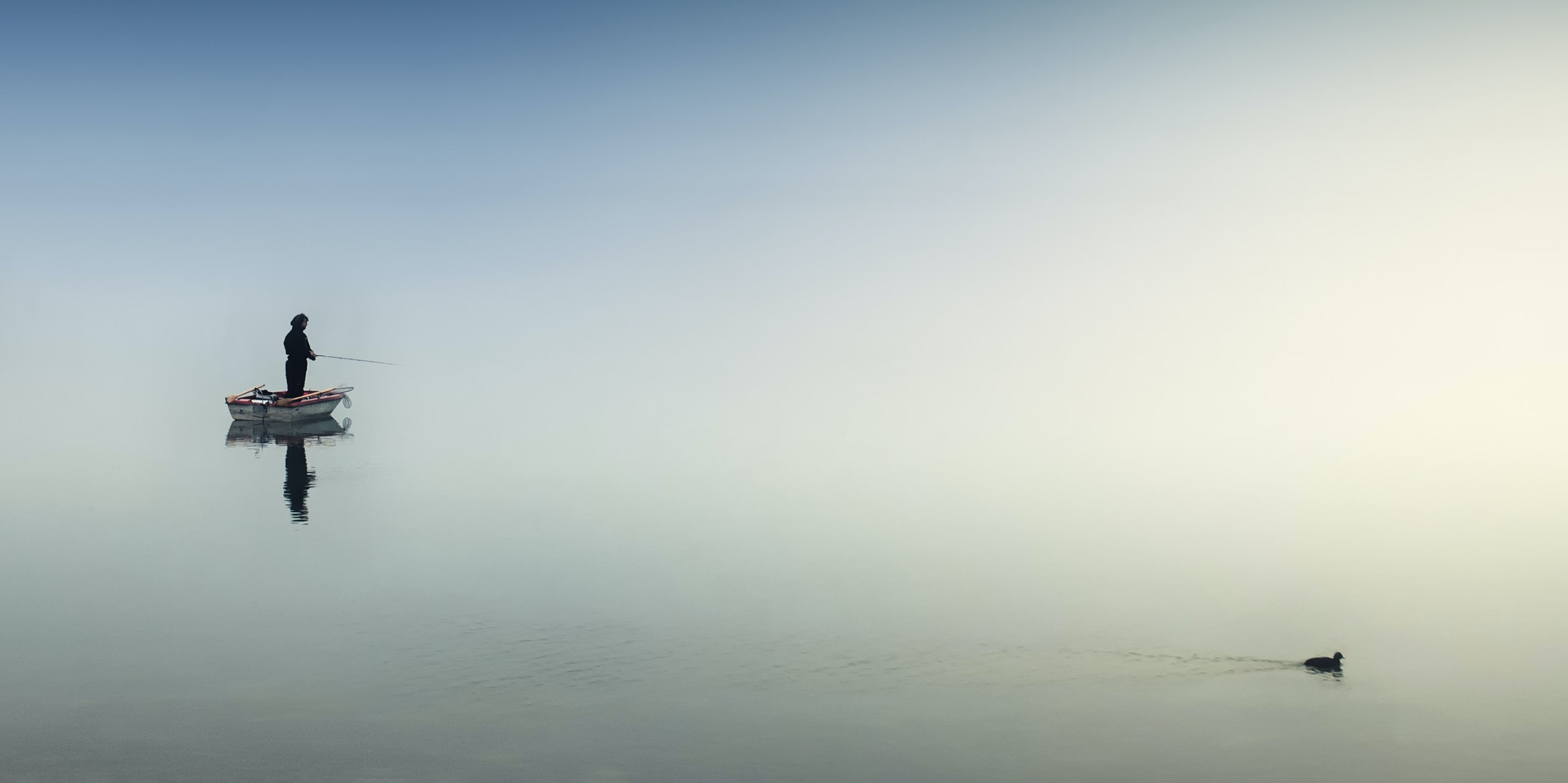 Image of a man standing in a boat fishing