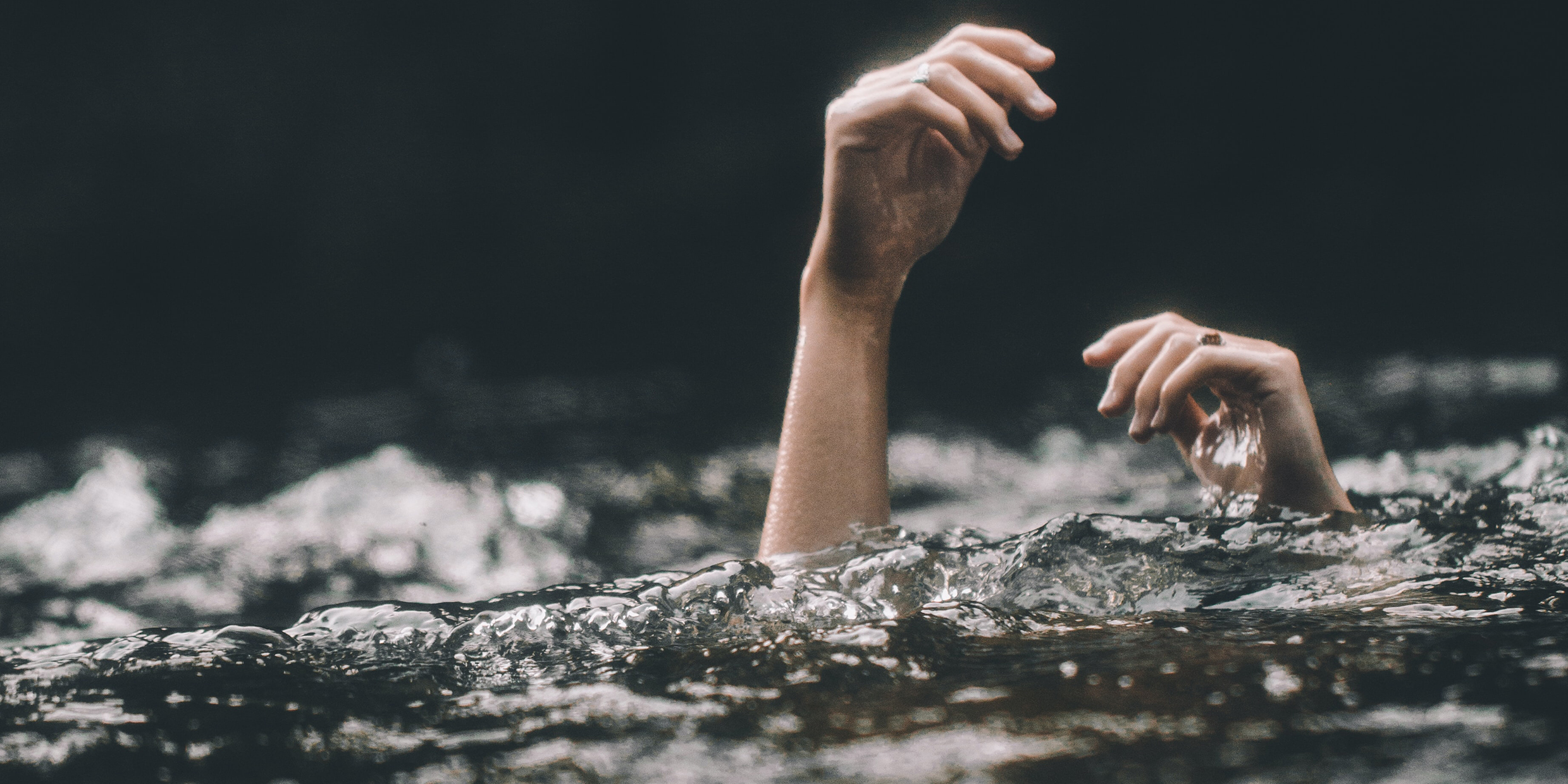 Image of hands reaching up from below the surface of water