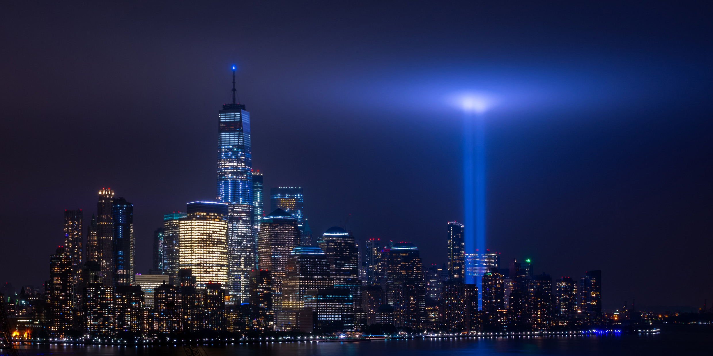 Photo of lower Manhattan at night with two beams of light illuminated upwards