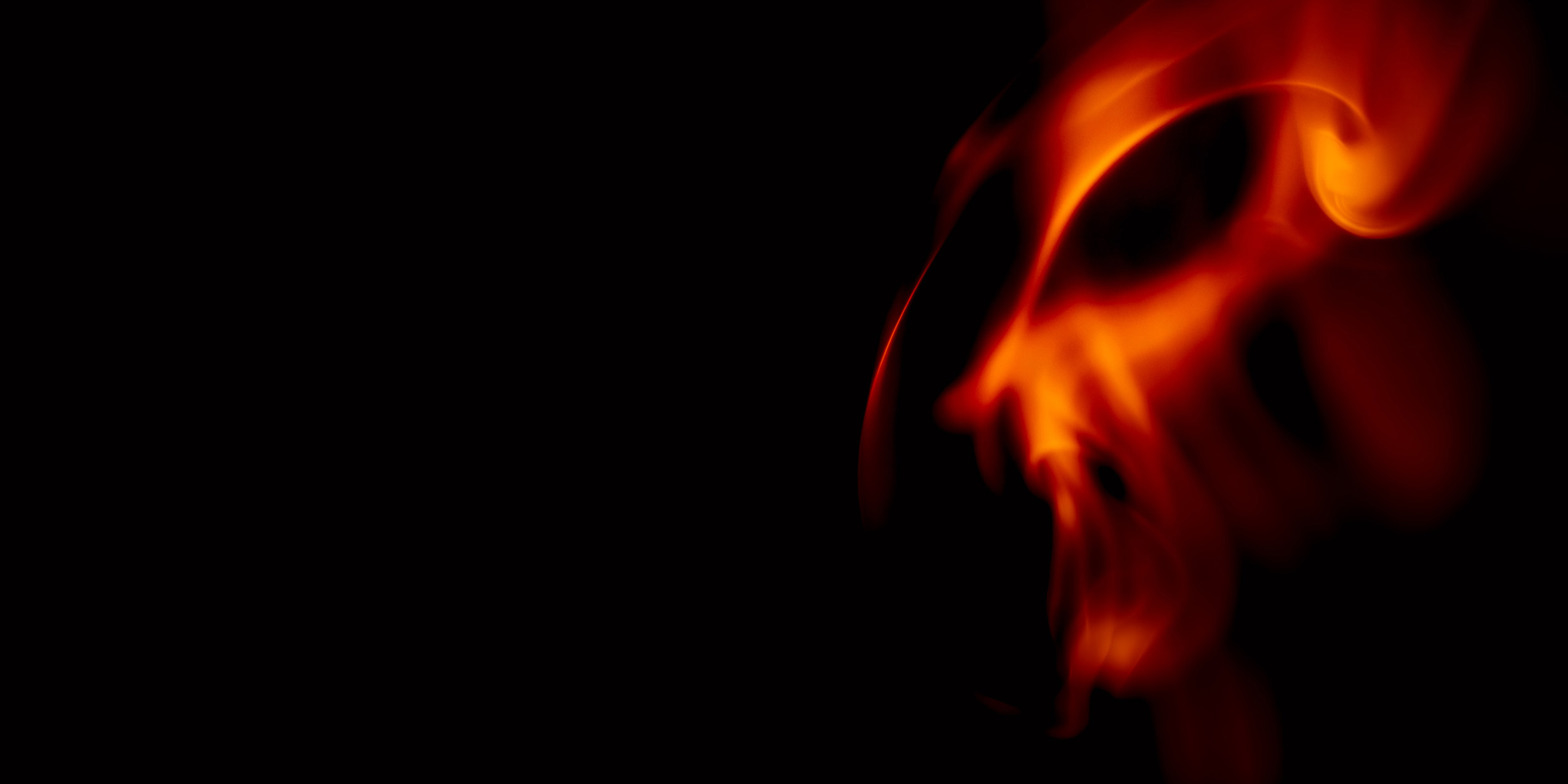 Image of orange flames on a black background that is evocative of the face of an infernal being