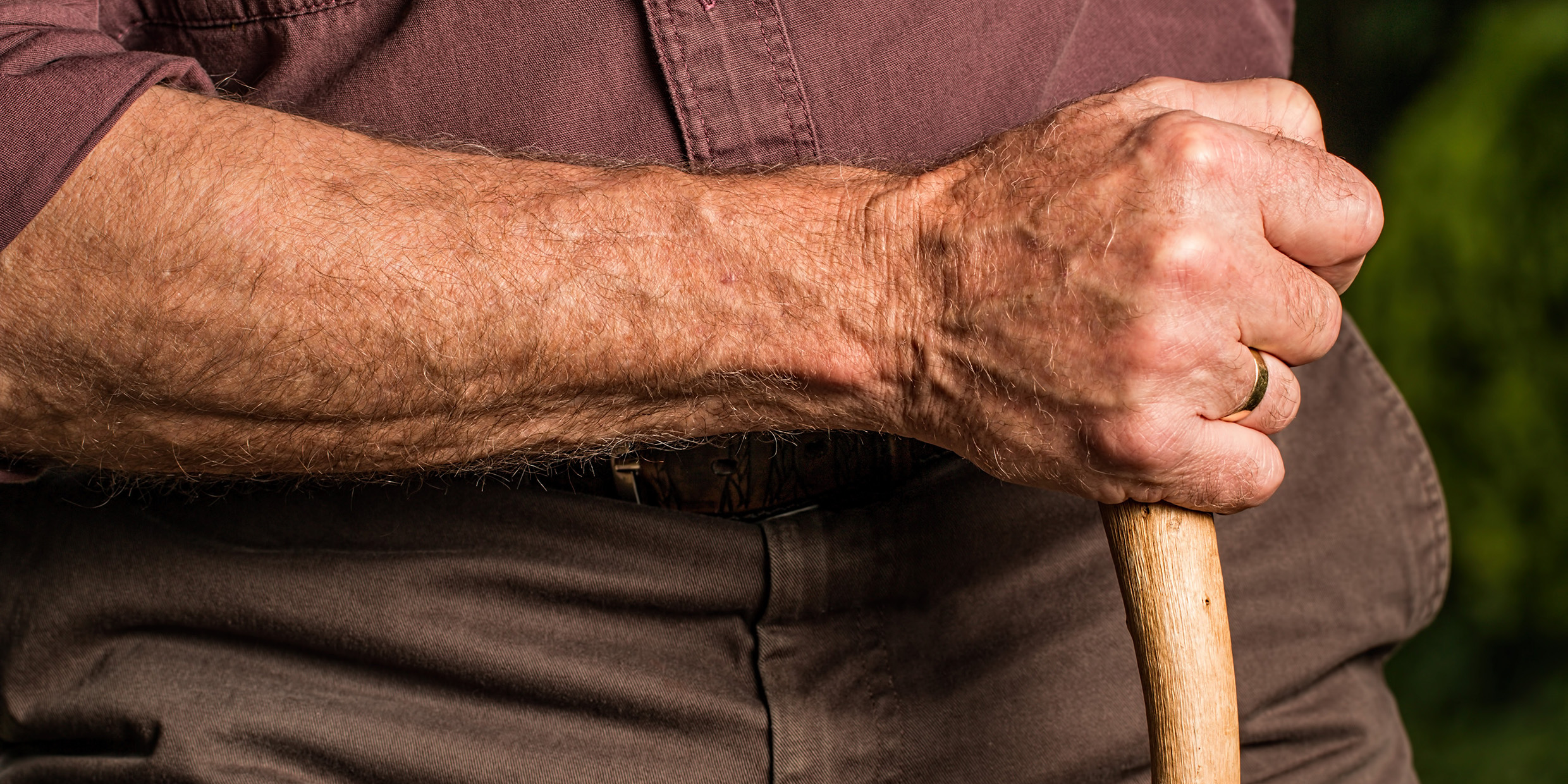 Close up image of an old man's hand holding a cane