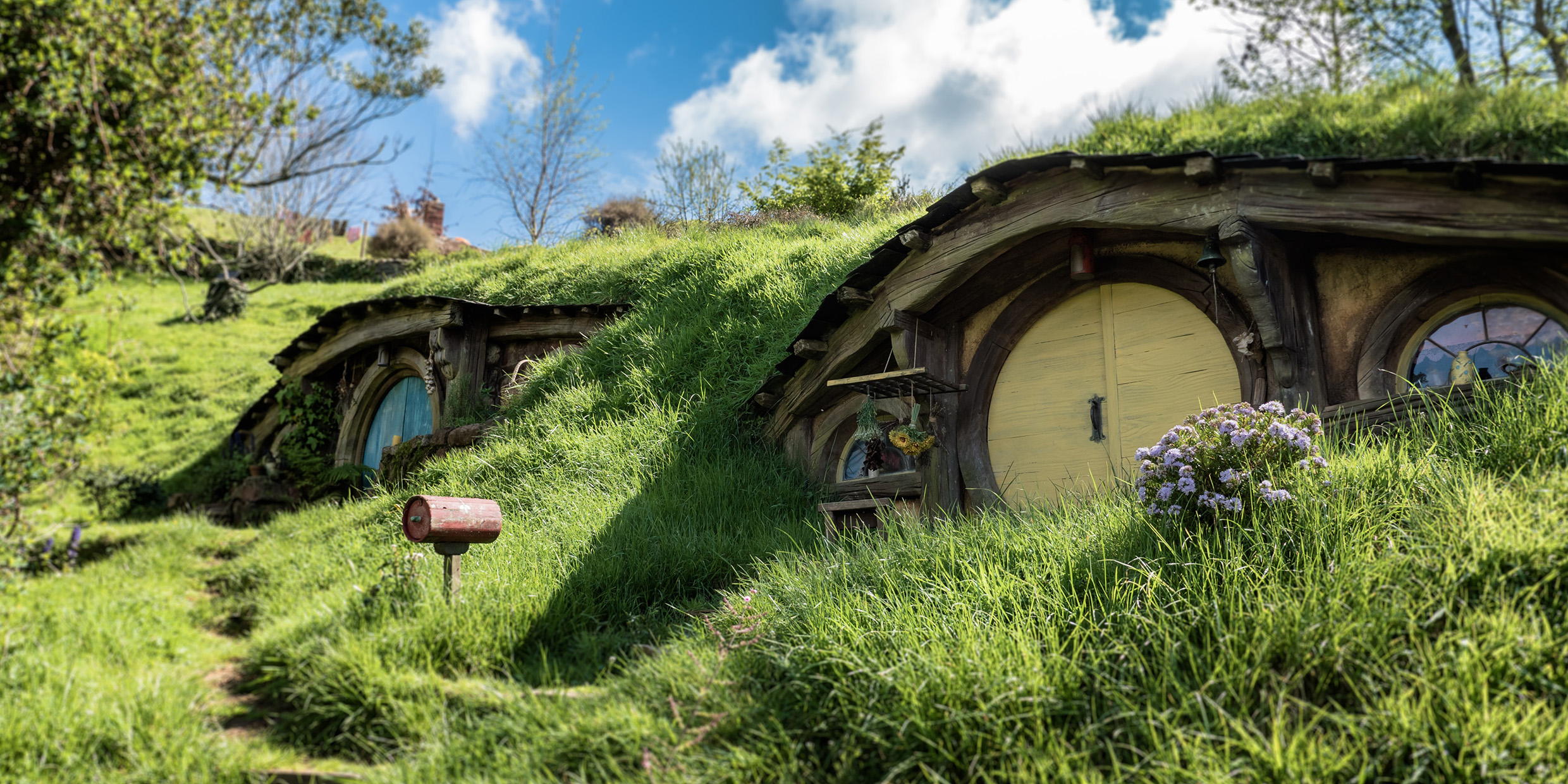 Image of two grass-roofed Hobbit dwellings from the “Lord of the Rings” movie set
