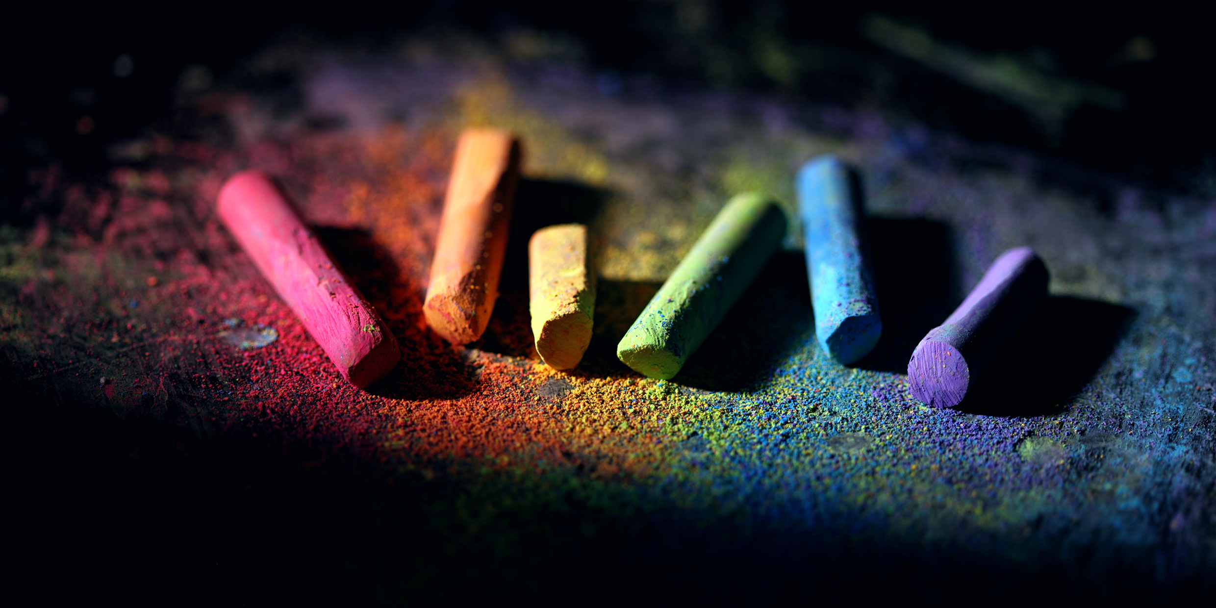 Image of an assortment of colored pieces of chalk against a dark background