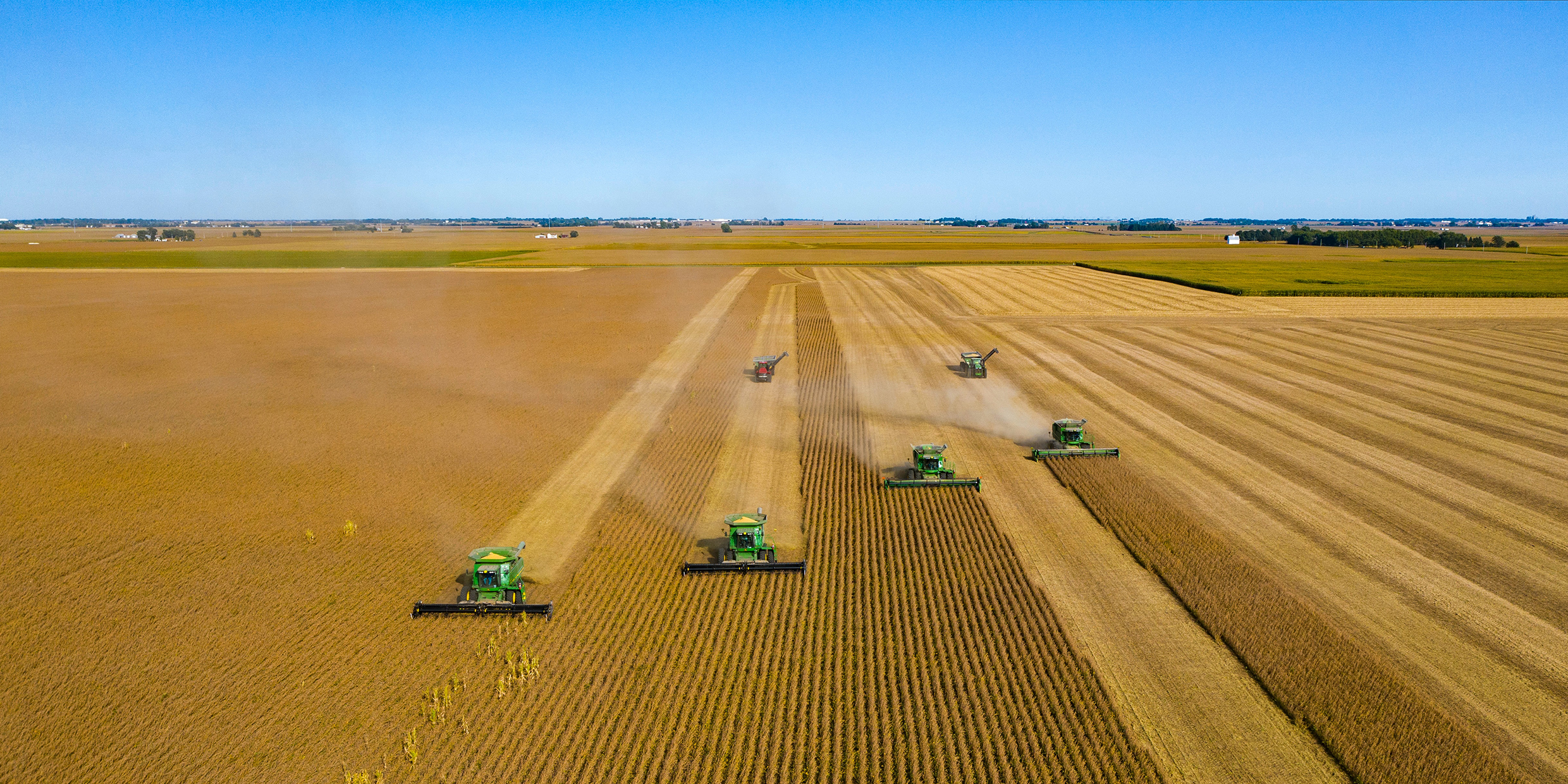 Aerial image of several mechanical harvesters working in a wide expanse of crops