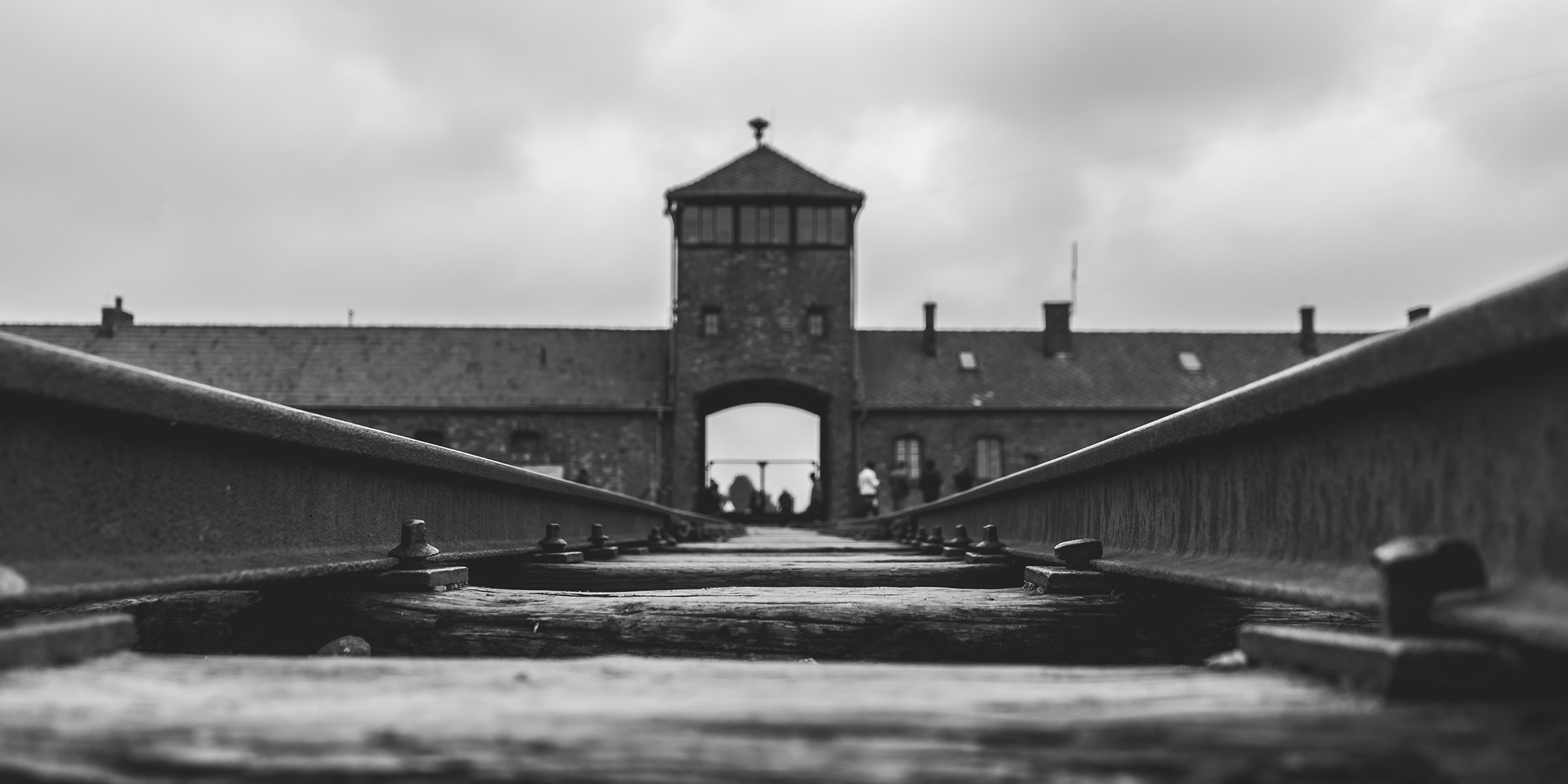 Black-and-white photo of the railroad leading into the gate of Auschwitz
