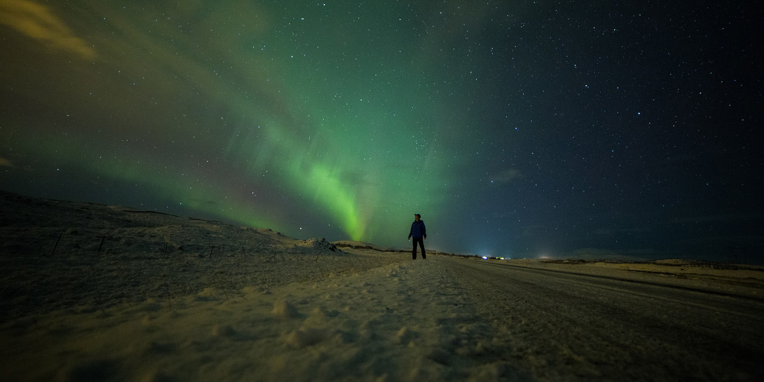 Silhouette of a person standing in the snow under the night sky