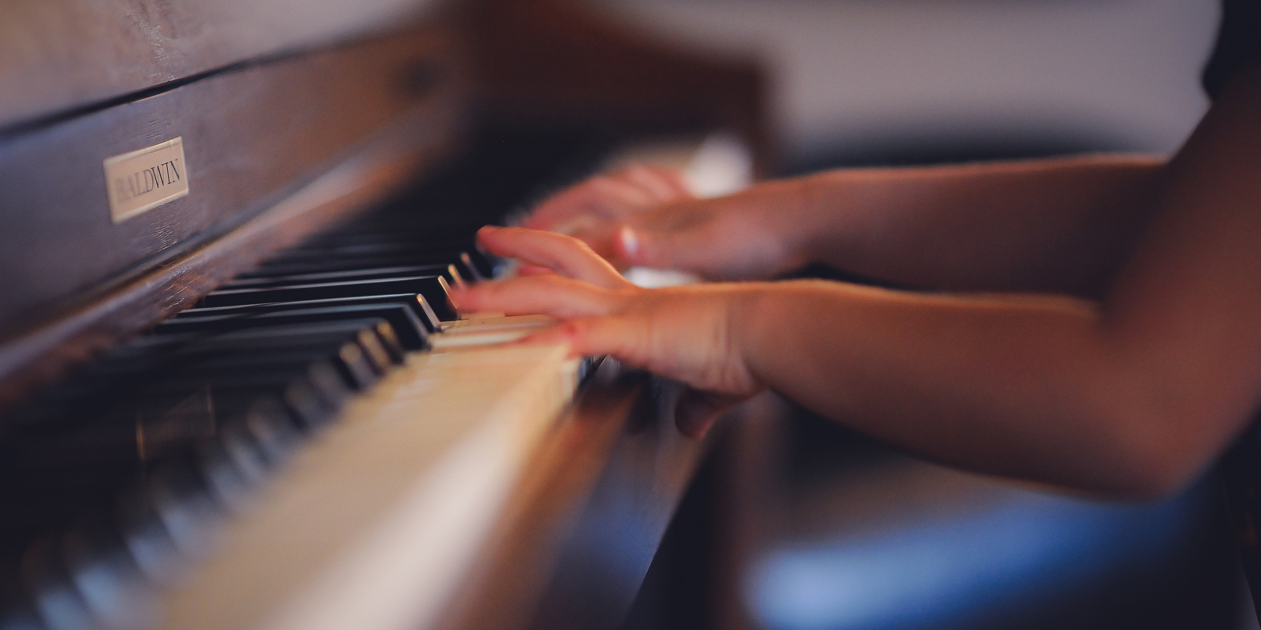 Image of the hands of a young child playing a piano