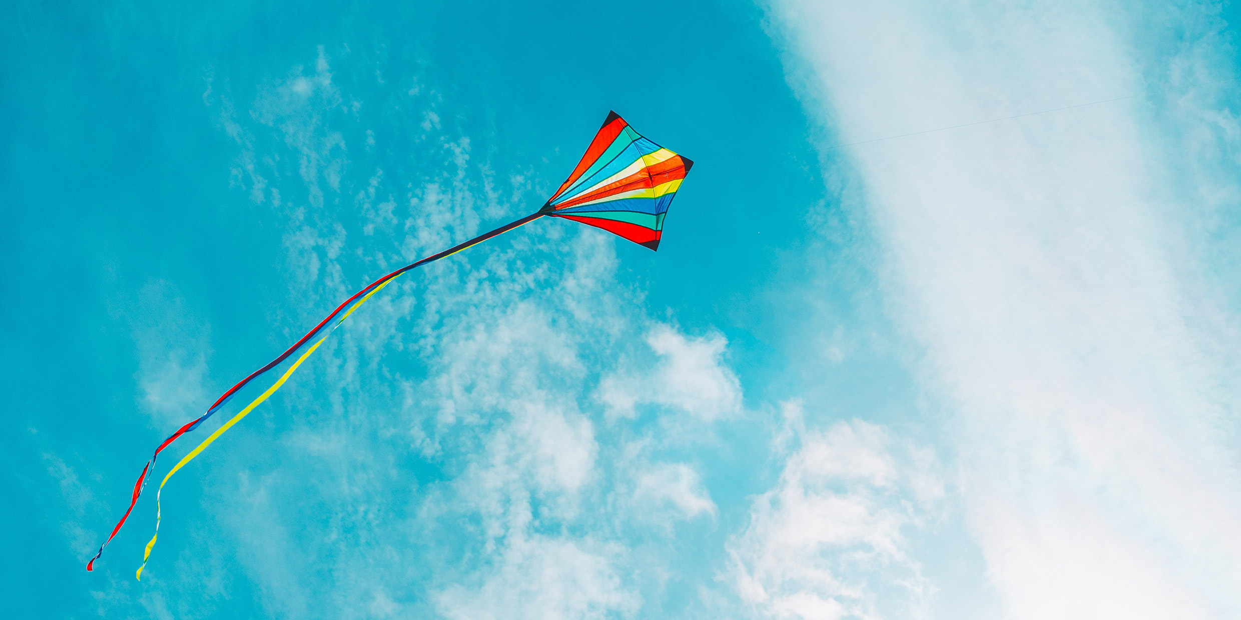 Image of a brightly-colored kite flying in a blue sky