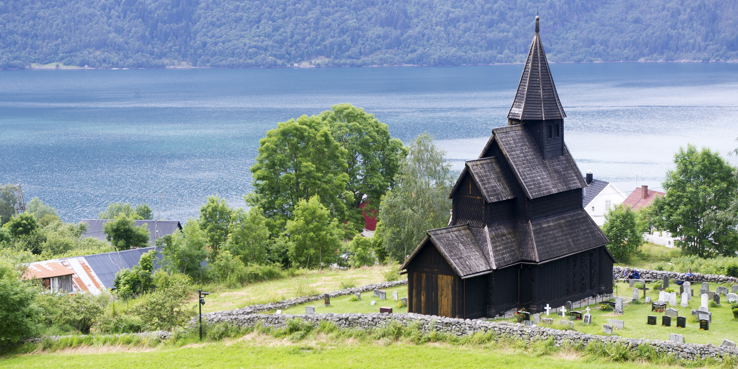 Image of a medieval stave church beside a fjord in Norway