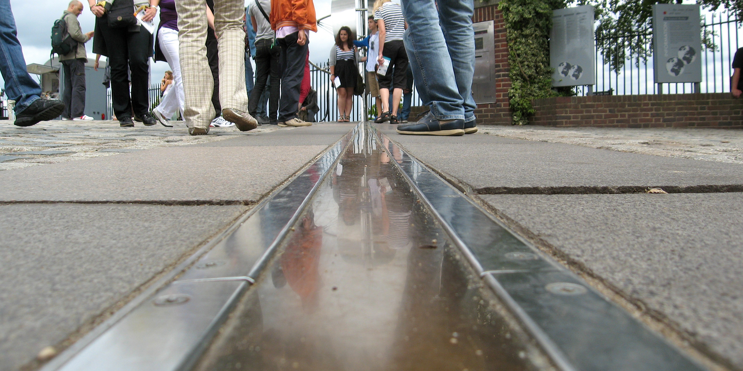 Image of a line of longitude marked in pavement with tourists nearby