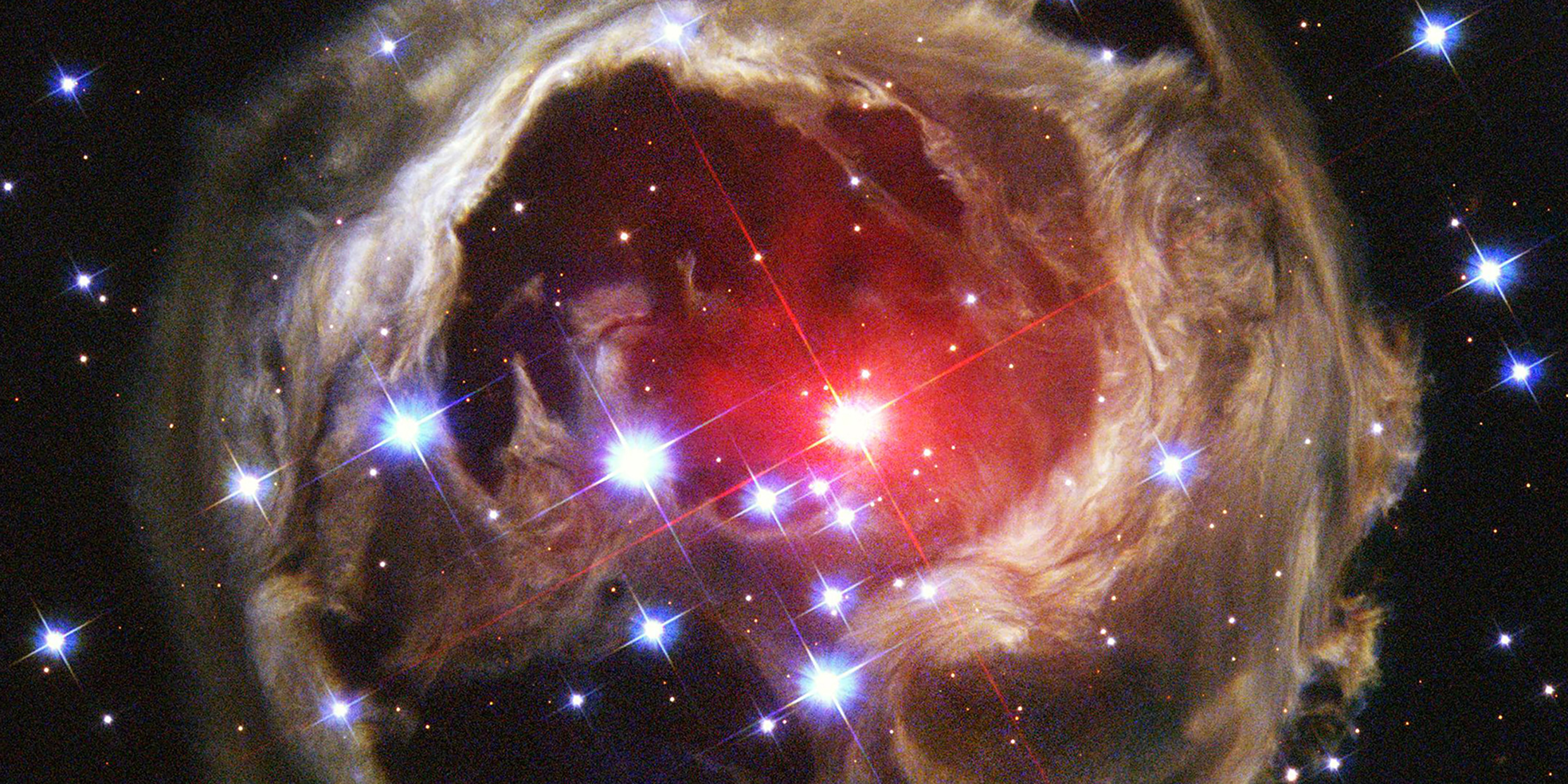 Astronomical image of a ruby-red star surrounded by a dust cloud