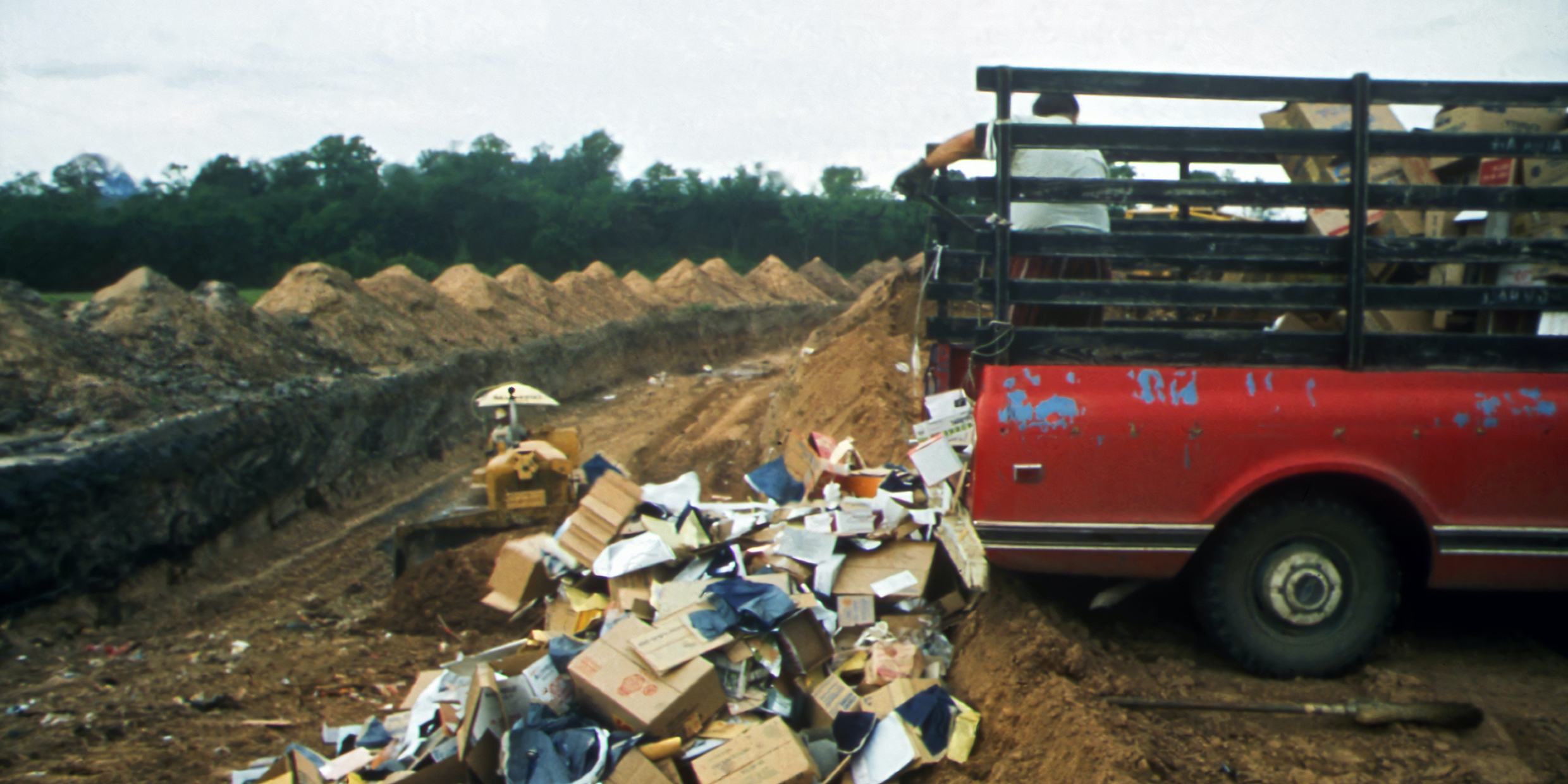 Image of a man unloading garbage from a pickup truck into a landfill