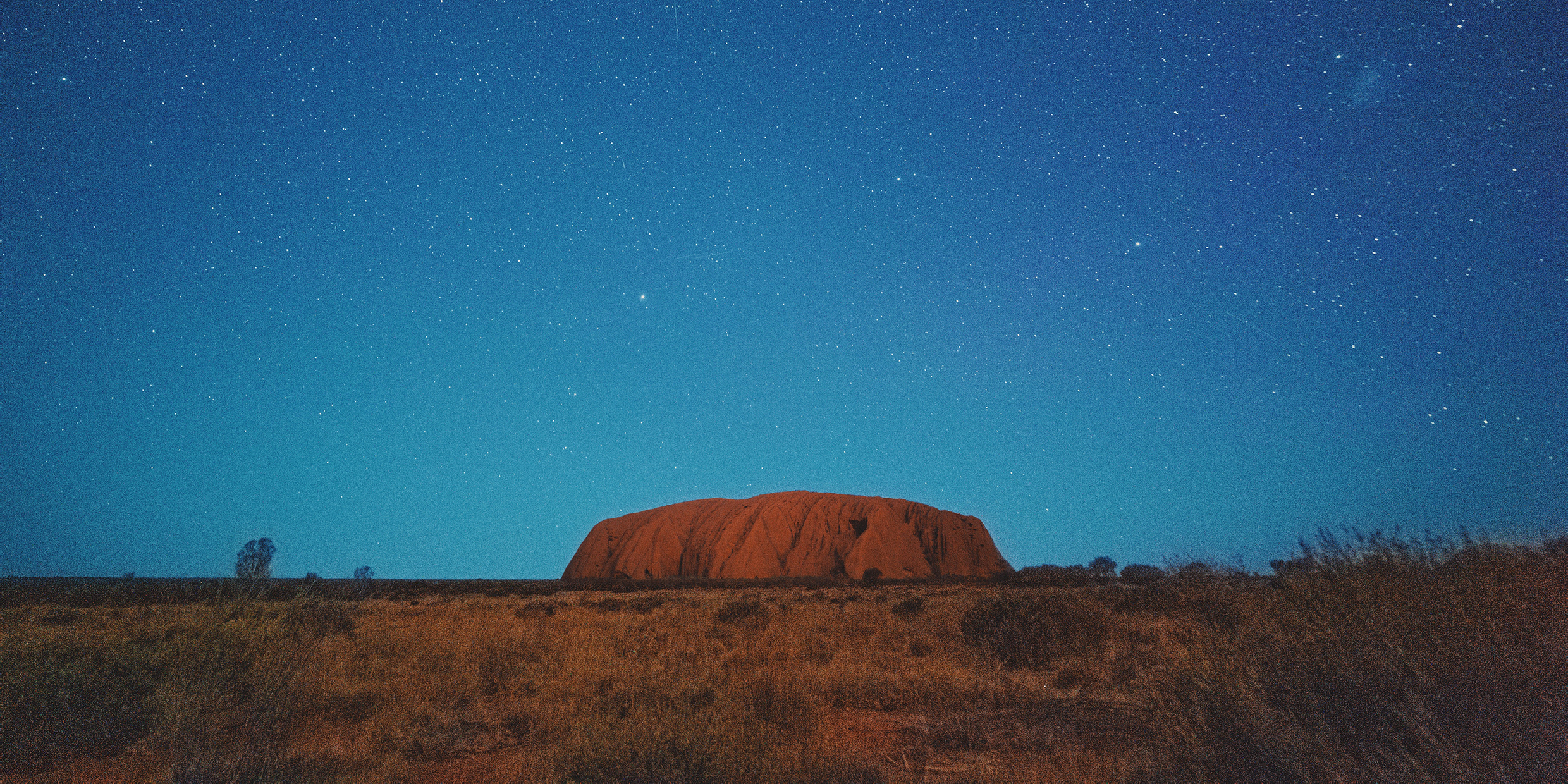 Image of a stone formation rising from the outback under the stars