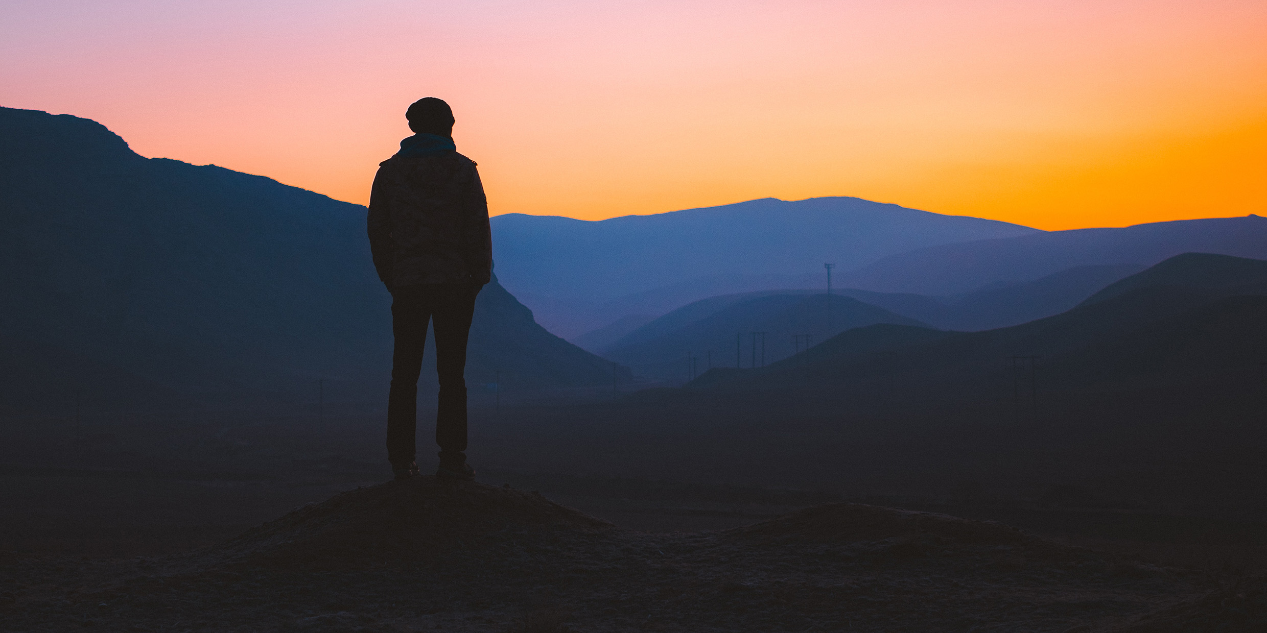 Image of a man silhouetted by the dawn sky